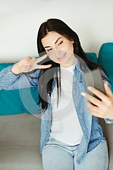 Woman showing victory gesture during video call