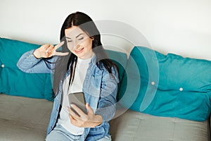 Woman showing victory gesture during video call