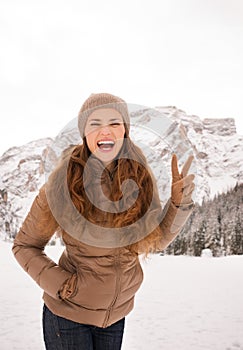 Woman showing victory outdoors among snow-capped mountains