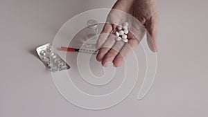 A woman showing white tablets in hand and throwing it down - empty blister, siringe and vial on white table background