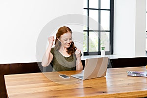 Woman showing yeah gesture near laptop