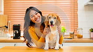 A woman is shown in a friendly interaction with her dog, a playful beagle