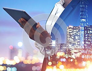 Multiple exposure of female programmer with tablet, digital binary code and night city.