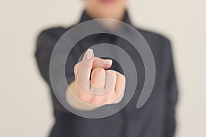 Woman shows beckoning sign in camera on beige background