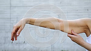 A woman shows the flabby muscles of the arm.  Flabby Arm Syndrome FAS.