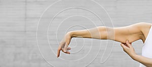 A woman shows the flabby muscles of the arm. Flabby Arm Syndrome (FAS). Banner,