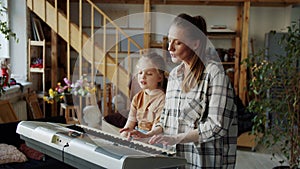 A woman shows the girl the basics of singing and uses the piano