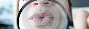 Woman shows her lips through magnifying glass