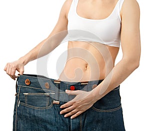 Woman shows her weight loss by wearing an old jeans, isolated on