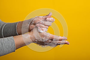 Woman shows how to soap hands with soap. Studio. yellow bright background, isolated. hand disinfection to prevent coronavirus