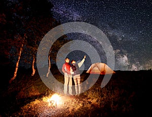 Woman shows the man up at the evening starry sky with Milky way