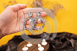 The woman shows off on her hand beautiful fashionable earrings with plastic, pearls and a clasp made of crumpled metal