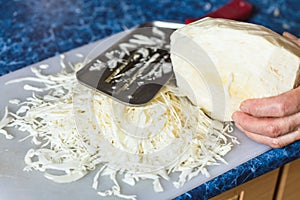 Woman shreds cabbage on cutting board