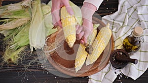 woman shucking shell hull fresh corn cob in her kitchen