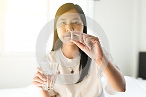 Woman sick with capsules putting in her mouth,female taking medicines and a glass of water