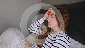 Woman sick with flu coughing and blowing her nose on her bed at home having sore throat, fever and headache. Young