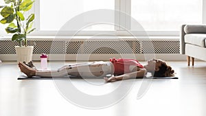 Woman side view lying on yoga mat practicing corpse pose photo