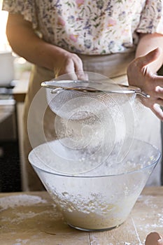 Woman sieving flour into a bowl