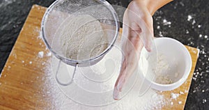 Woman sieving flour from the bowl on the wooden board 4k