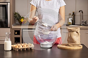 Woman sieving and measuring flour