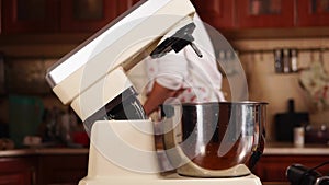 Woman is sifting the flour in a bowl of mixer and putting large whisk