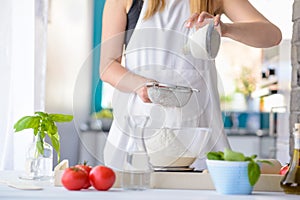 Woman sifting flour through sieve.