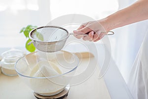 Woman sifting flour through sieve.