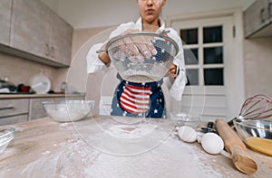 Woman sifting flour through sieve. Selective focus.