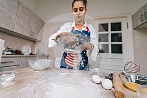 Woman sifting flour through sieve. Selective focus.