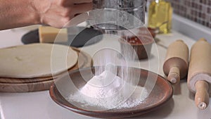 Woman sifting flour through sieve. Selective focus