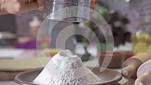 Woman sifting flour through sieve. Selective focus