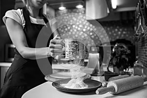 Woman sifting flour through sieve. Selective focus