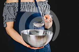 Woman sifting flour through sieve. Selective focus