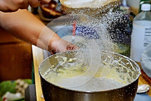 Woman sifts the flour in bowl with dough. Making cake dough