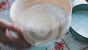 A woman sifts the flour through a sieve