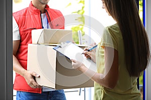 Woman signing for delivered parcels on doorstep. Courier service