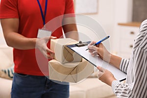 Woman signing for delivered parcels at home. Courier service