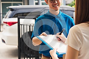 Woman signing delivery in clipboard get her package from service courier man