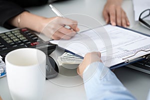 Woman signing documents for a batch of hundred dollar bills