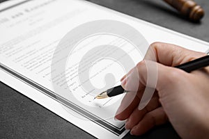 Woman signing last will and testament at grey table, closeup