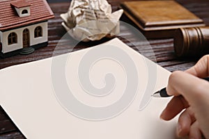 Woman signing last will and testament at wooden table, closeup