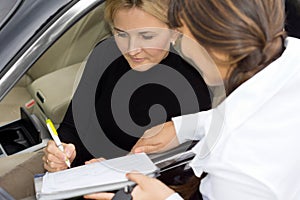 Woman signing for ownership of new car