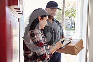 Woman Signing For Package From Courier At Home