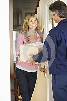 Woman Signing For Package Delivered By Courier