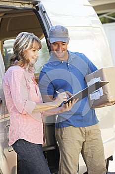 Woman Signing For Packager Delivered By Courier photo