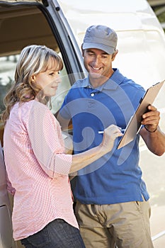 Woman Signing For Packager Delivered By Courier
