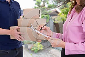 Woman signing receipt of delivery package at home.