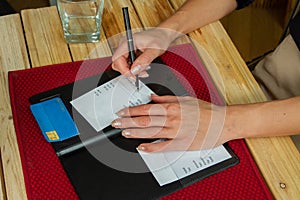 Woman Signs Credit Card Receipt at Restaurant