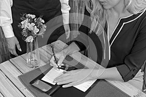 Woman Signs Credit Card Receipt at Restaurant