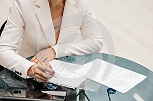 Woman signs document, emphasis on female hand and pen, supplying signature on official paper, signing name on statement with legal photo